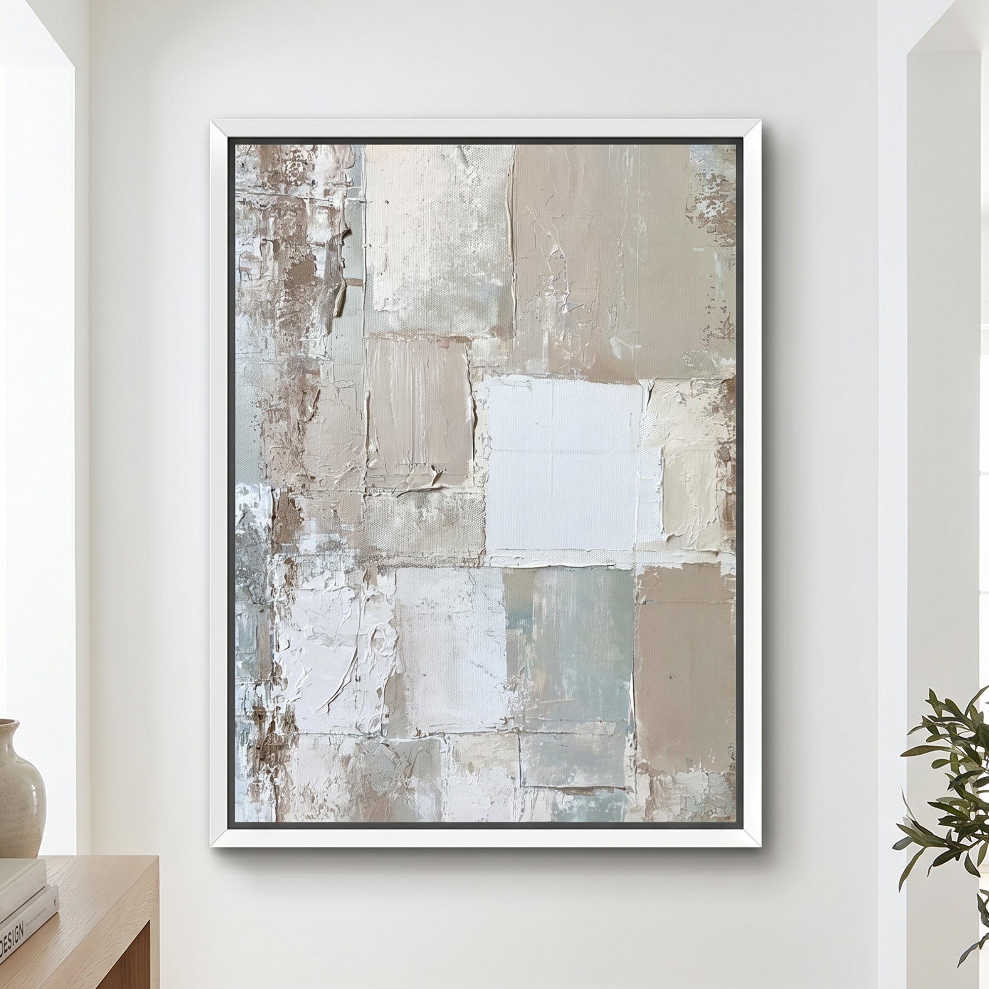 Framed abstract wall art hanging on a white wall, featuring a patchwork of textured blocks in beige, gray, off-white, and muted blue-green tones.