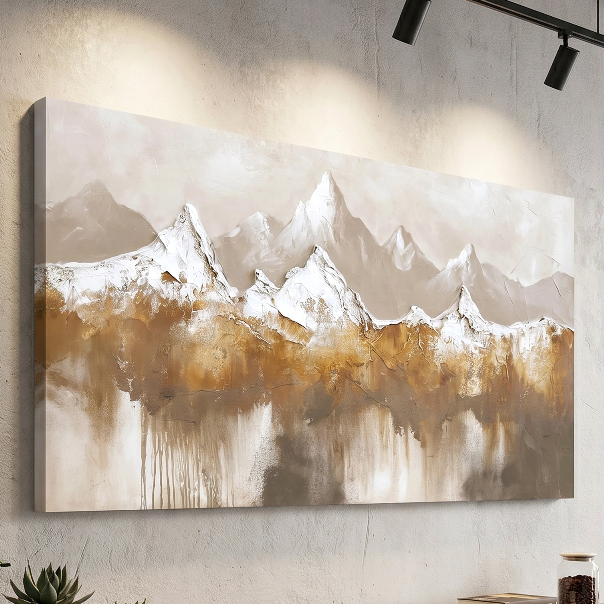 A rectangular canvas wall art print featuring an abstract mountain landscape in beige, brown, white, and gray tones, displayed on a textured light wall under black track lighting.