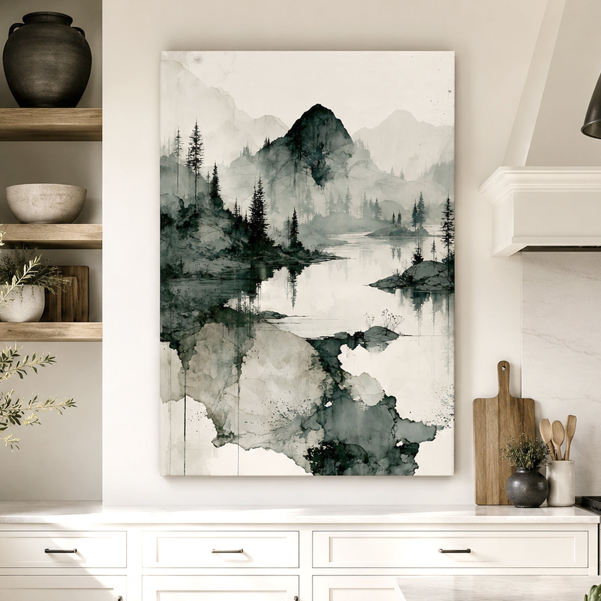 A vertical canvas wall art print featuring a black and white ink-style landscape of a lake, trees, and mountains, displayed on a white kitchen wall above a countertop.